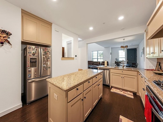 kitchen with kitchen peninsula, cream cabinetry, stainless steel appliances, and dark wood-type flooring