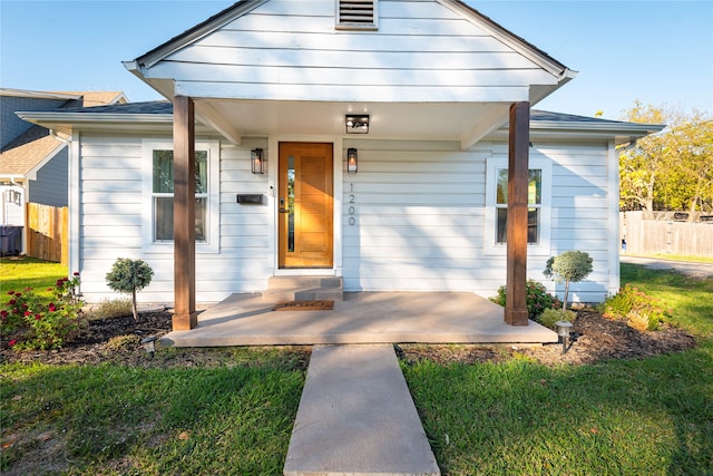 bungalow-style home with covered porch, a front yard, and fence