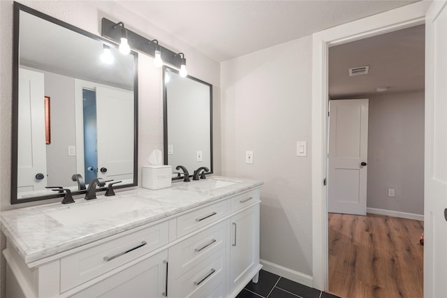 bathroom with visible vents, a sink, baseboards, and double vanity