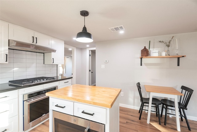 kitchen featuring visible vents, butcher block counters, stainless steel appliances, under cabinet range hood, and white cabinetry