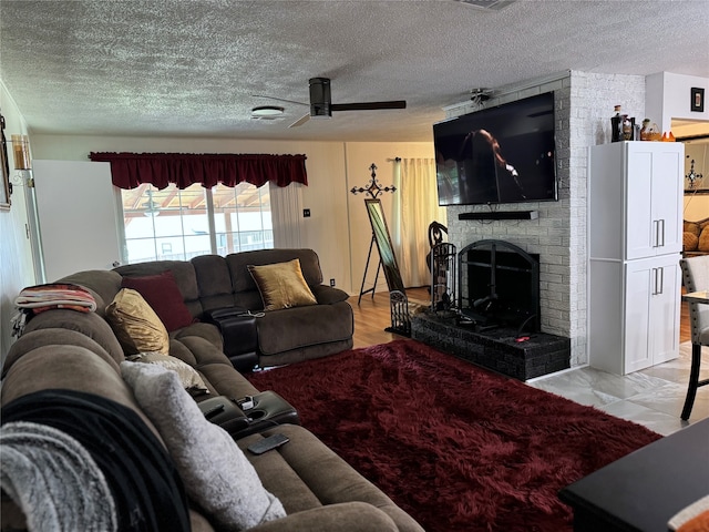 living room with ceiling fan, a fireplace, a textured ceiling, and light hardwood / wood-style flooring