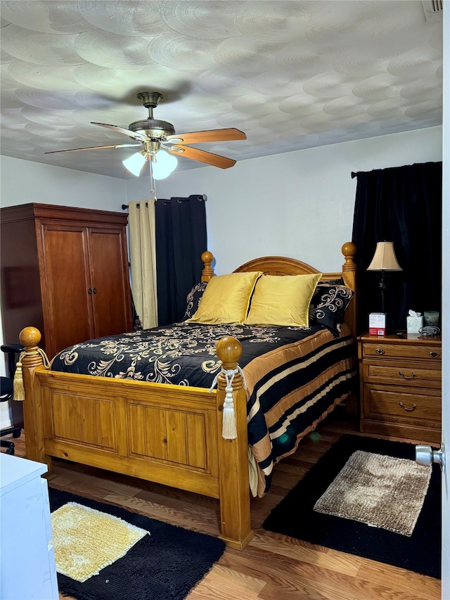 bedroom featuring hardwood / wood-style floors, a textured ceiling, and ceiling fan