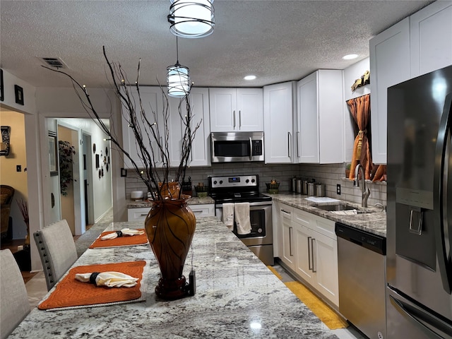 kitchen with white cabinets, light stone counters, sink, and appliances with stainless steel finishes