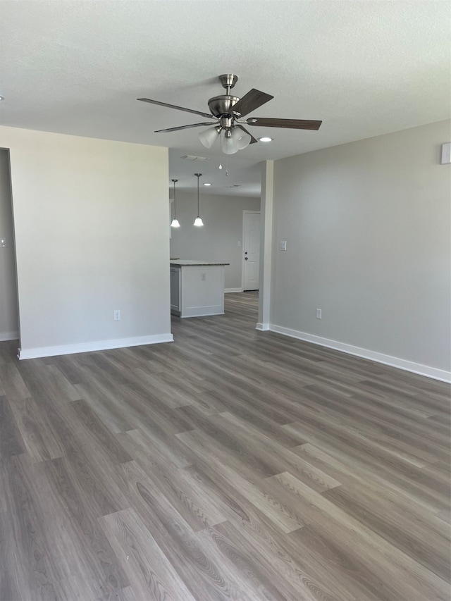 unfurnished living room with dark hardwood / wood-style floors, ceiling fan, and a textured ceiling