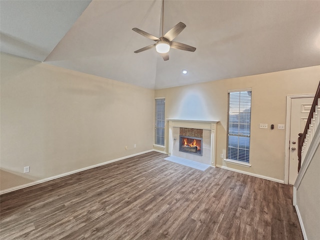 unfurnished living room with ceiling fan, dark hardwood / wood-style flooring, lofted ceiling, and a tiled fireplace