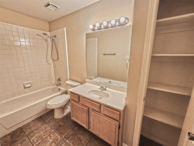 full bathroom with vanity, tiled shower / bath combo, and toilet