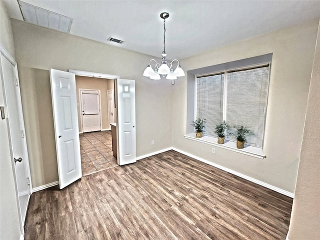 unfurnished dining area featuring hardwood / wood-style flooring and an inviting chandelier