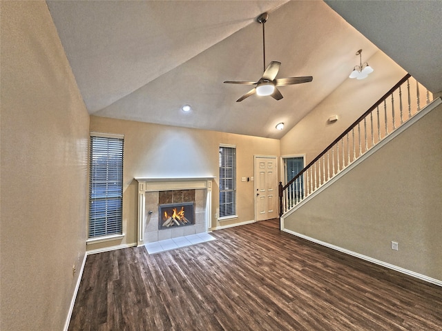 unfurnished living room with ceiling fan, dark hardwood / wood-style flooring, high vaulted ceiling, and a tiled fireplace