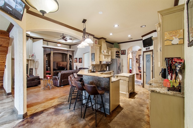 kitchen with pendant lighting, cream cabinets, ceiling fan, kitchen peninsula, and a breakfast bar area