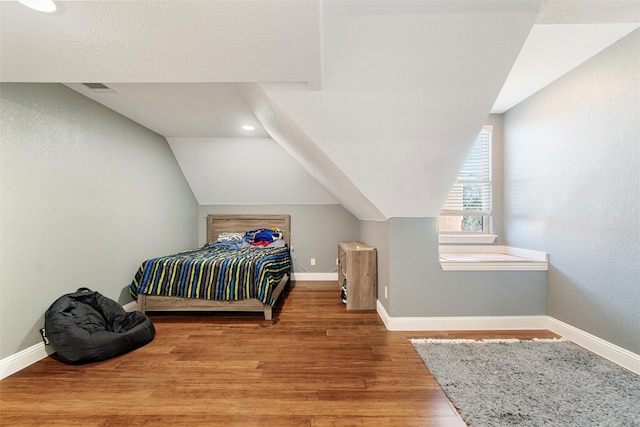 bedroom featuring wood-type flooring and vaulted ceiling