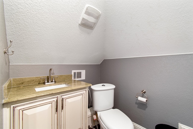 bathroom featuring vanity, toilet, and lofted ceiling