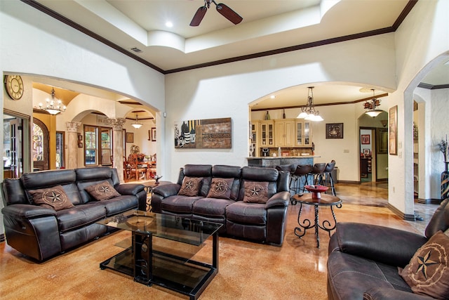 living room featuring ceiling fan with notable chandelier, a tray ceiling, and crown molding