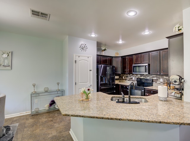 kitchen with kitchen peninsula, light stone counters, sink, and appliances with stainless steel finishes