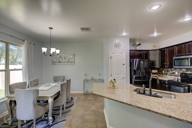 kitchen with light stone countertops, stainless steel appliances, sink, an inviting chandelier, and hanging light fixtures