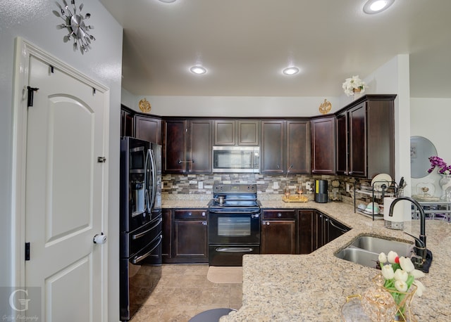 kitchen with black appliances, sink, decorative backsplash, dark brown cabinets, and light stone counters