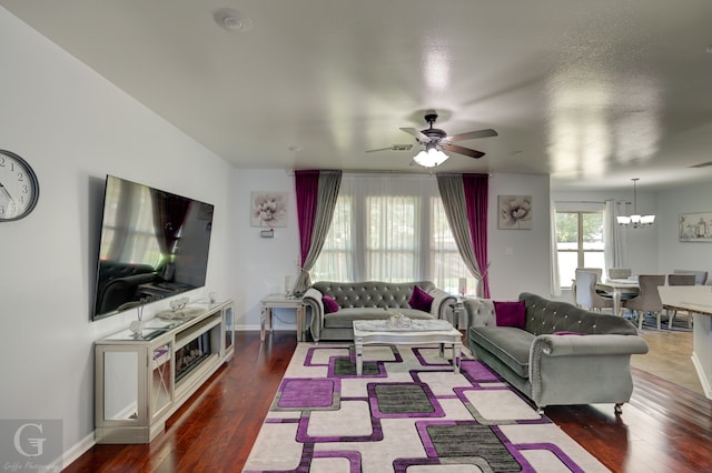 living room featuring ceiling fan with notable chandelier and hardwood / wood-style flooring