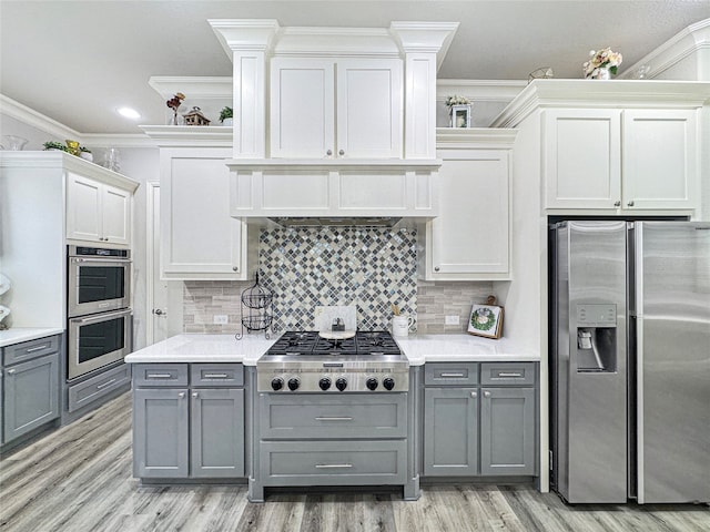 kitchen featuring gray cabinetry, light wood-type flooring, ornamental molding, white cabinetry, and stainless steel appliances