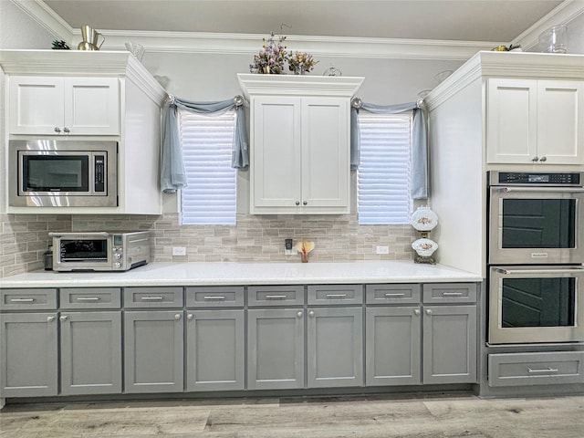 kitchen with gray cabinets, crown molding, and stainless steel appliances