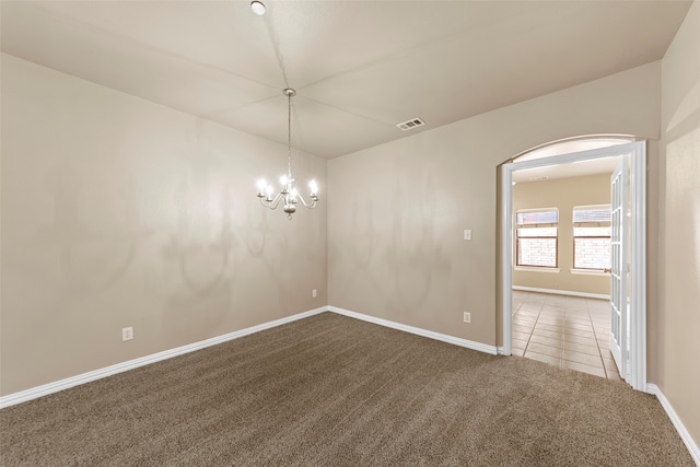 empty room with carpet floors and an inviting chandelier