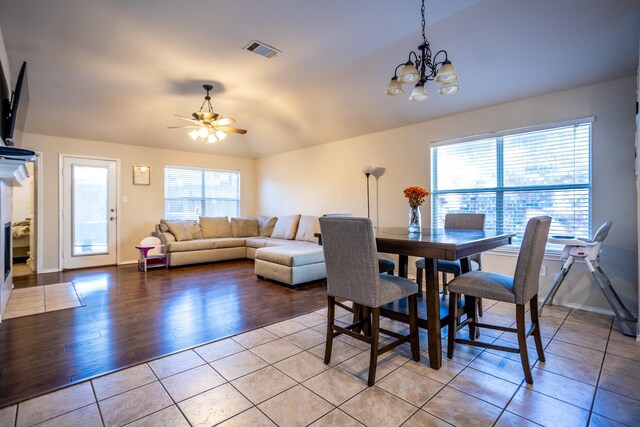 dining space with ceiling fan with notable chandelier, light hardwood / wood-style floors, and a healthy amount of sunlight