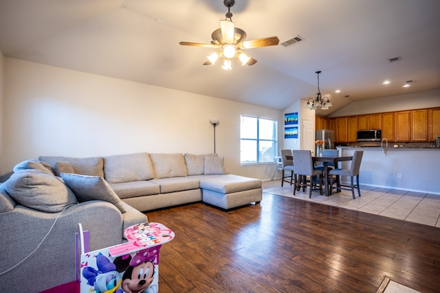 living room featuring light hardwood / wood-style flooring, ceiling fan with notable chandelier, and vaulted ceiling