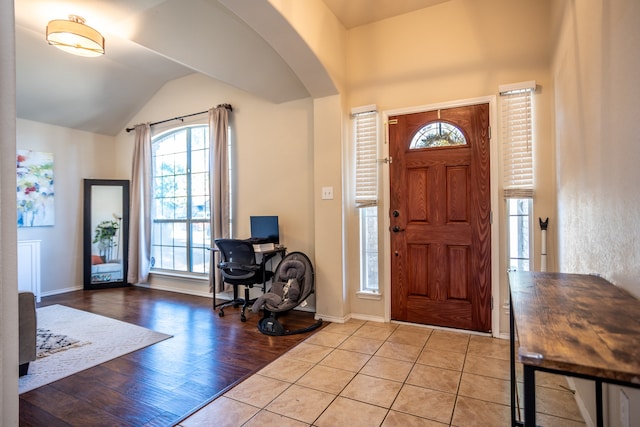 foyer entrance with light hardwood / wood-style floors and vaulted ceiling