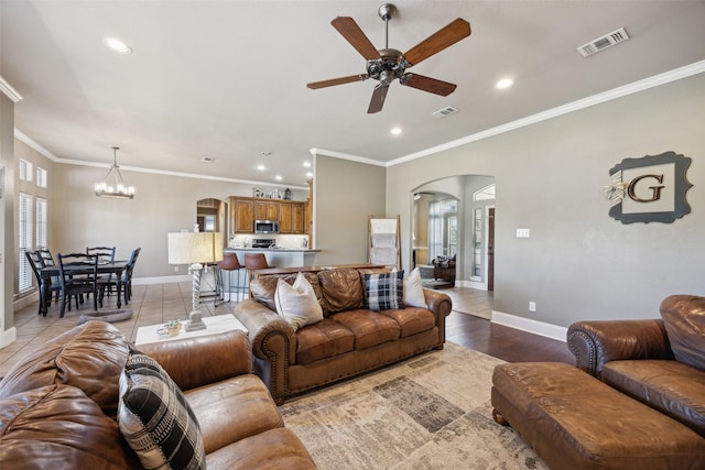 living room with ceiling fan with notable chandelier, light wood-type flooring, and ornamental molding