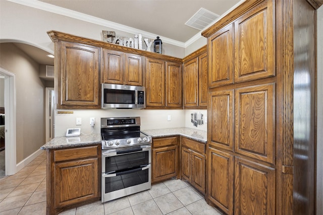 kitchen featuring stainless steel appliances, stone countertops, light tile patterned floors, and ornamental molding