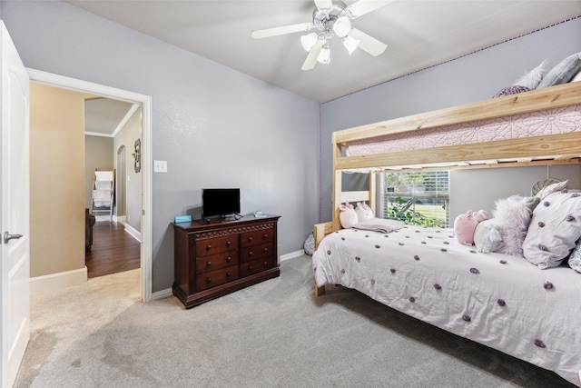 carpeted bedroom featuring ceiling fan and crown molding