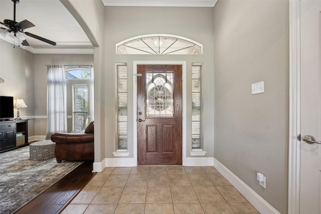 foyer entrance featuring ceiling fan, crown molding, and light tile patterned flooring