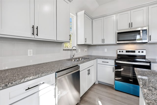 kitchen featuring light stone countertops, white cabinetry, sink, light hardwood / wood-style floors, and appliances with stainless steel finishes