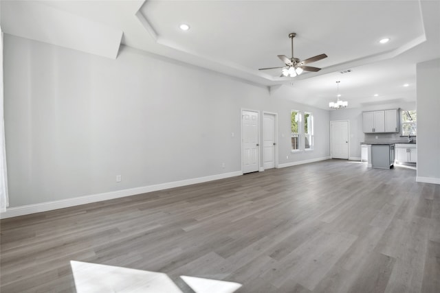 unfurnished living room featuring hardwood / wood-style floors and ceiling fan with notable chandelier