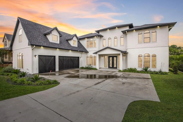 view of front of home featuring a garage, a yard, and french doors