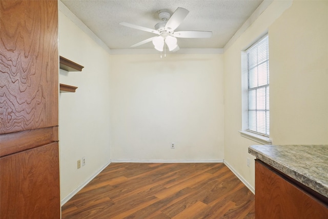 unfurnished dining area with ceiling fan, dark wood-type flooring, and a textured ceiling