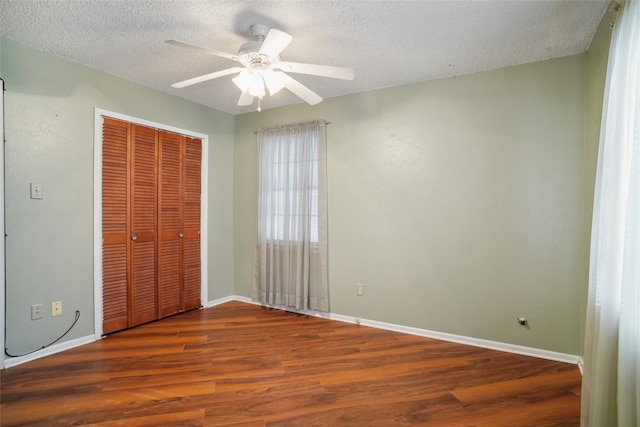 unfurnished bedroom with wood-type flooring, a textured ceiling, a closet, and ceiling fan