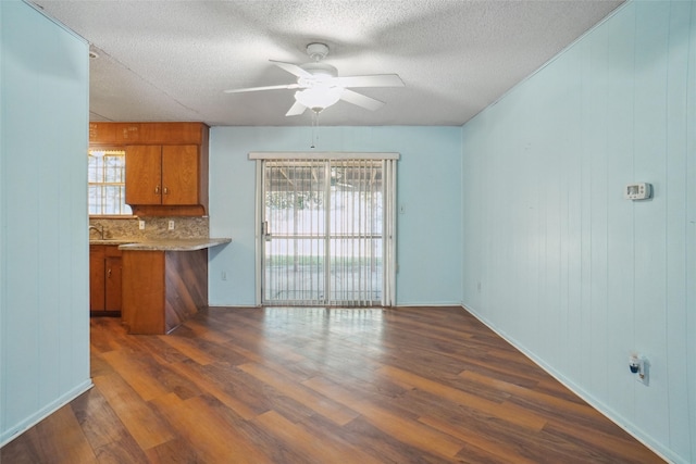 kitchen featuring kitchen peninsula, dark hardwood / wood-style flooring, backsplash, a textured ceiling, and ceiling fan