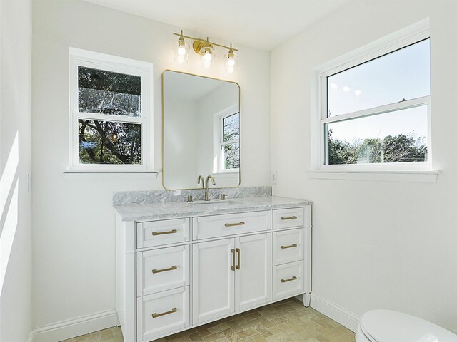 bathroom with vanity, a healthy amount of sunlight, and toilet