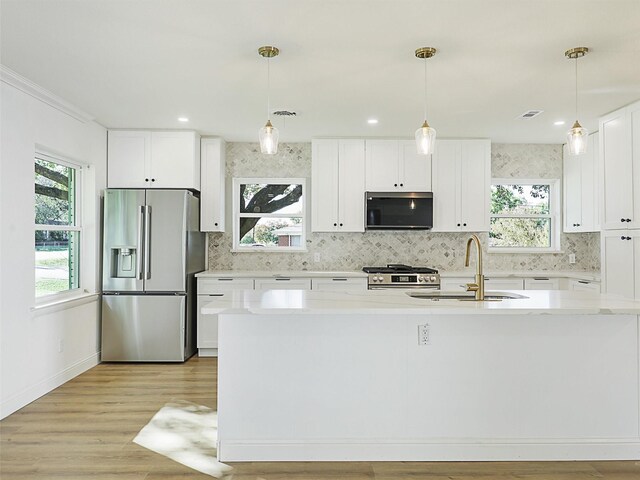 kitchen featuring white cabinets, appliances with stainless steel finishes, decorative light fixtures, and sink