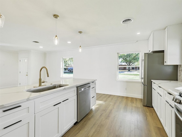 kitchen featuring sink, light stone counters, pendant lighting, stainless steel appliances, and white cabinets