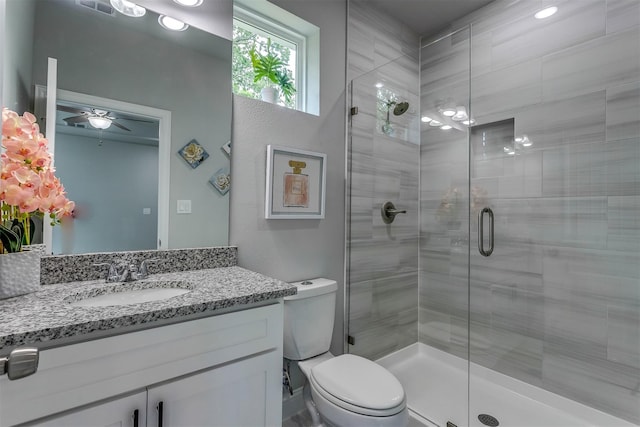 bathroom with vanity, a shower with door, toilet, and ceiling fan