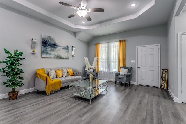 living room featuring wood-type flooring, a raised ceiling, and ceiling fan