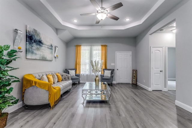 living room with ceiling fan, light hardwood / wood-style floors, and a tray ceiling