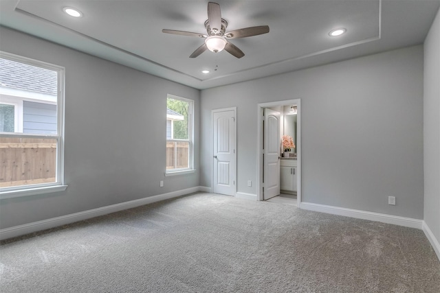 unfurnished bedroom with ceiling fan, ensuite bathroom, and light carpet