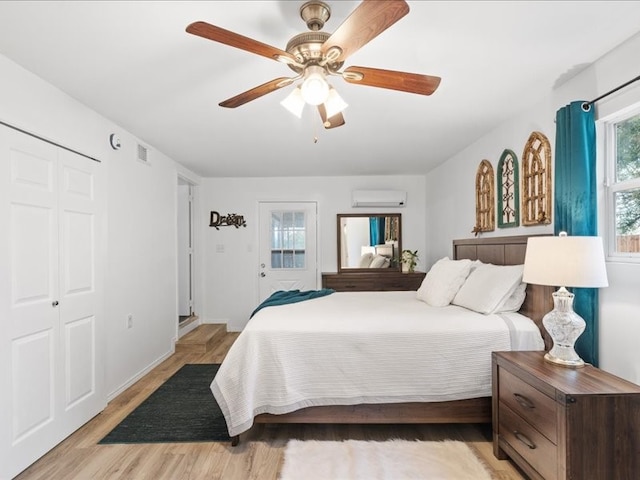 bedroom featuring ceiling fan, a closet, an AC wall unit, and light hardwood / wood-style flooring