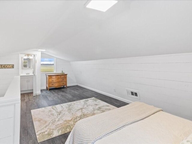 bedroom with dark hardwood / wood-style floors, vaulted ceiling, and ensuite bath