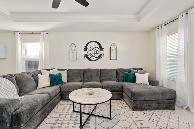 living room with a raised ceiling, ceiling fan, and crown molding