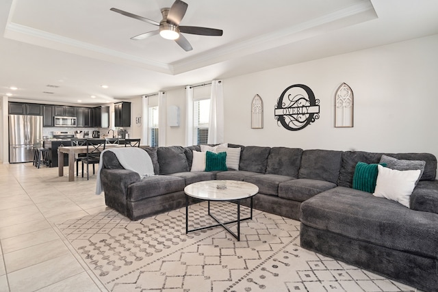 living room with sink, crown molding, ceiling fan, light tile patterned floors, and a tray ceiling