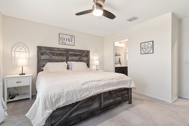 carpeted bedroom with ensuite bath and ceiling fan