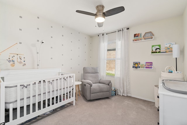 carpeted bedroom featuring ceiling fan and a nursery area