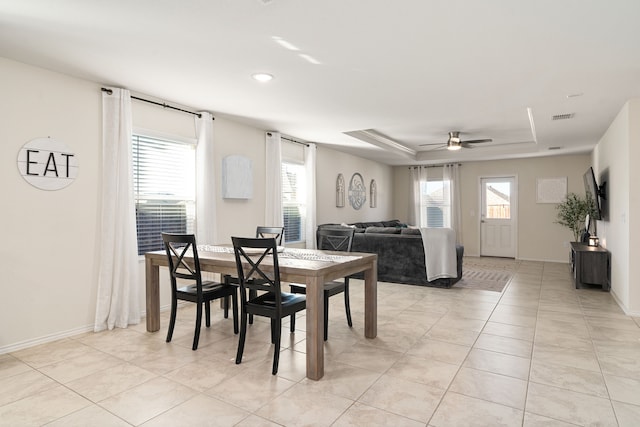 tiled dining room featuring a tray ceiling and ceiling fan